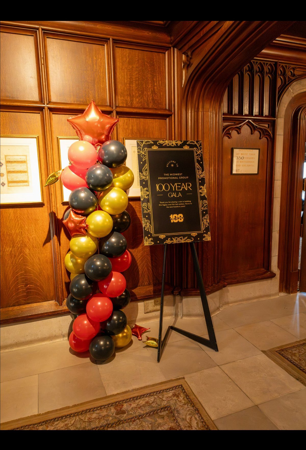 Red, gold, and black balloons stand next to a 100 Year Gala sign on an easel.