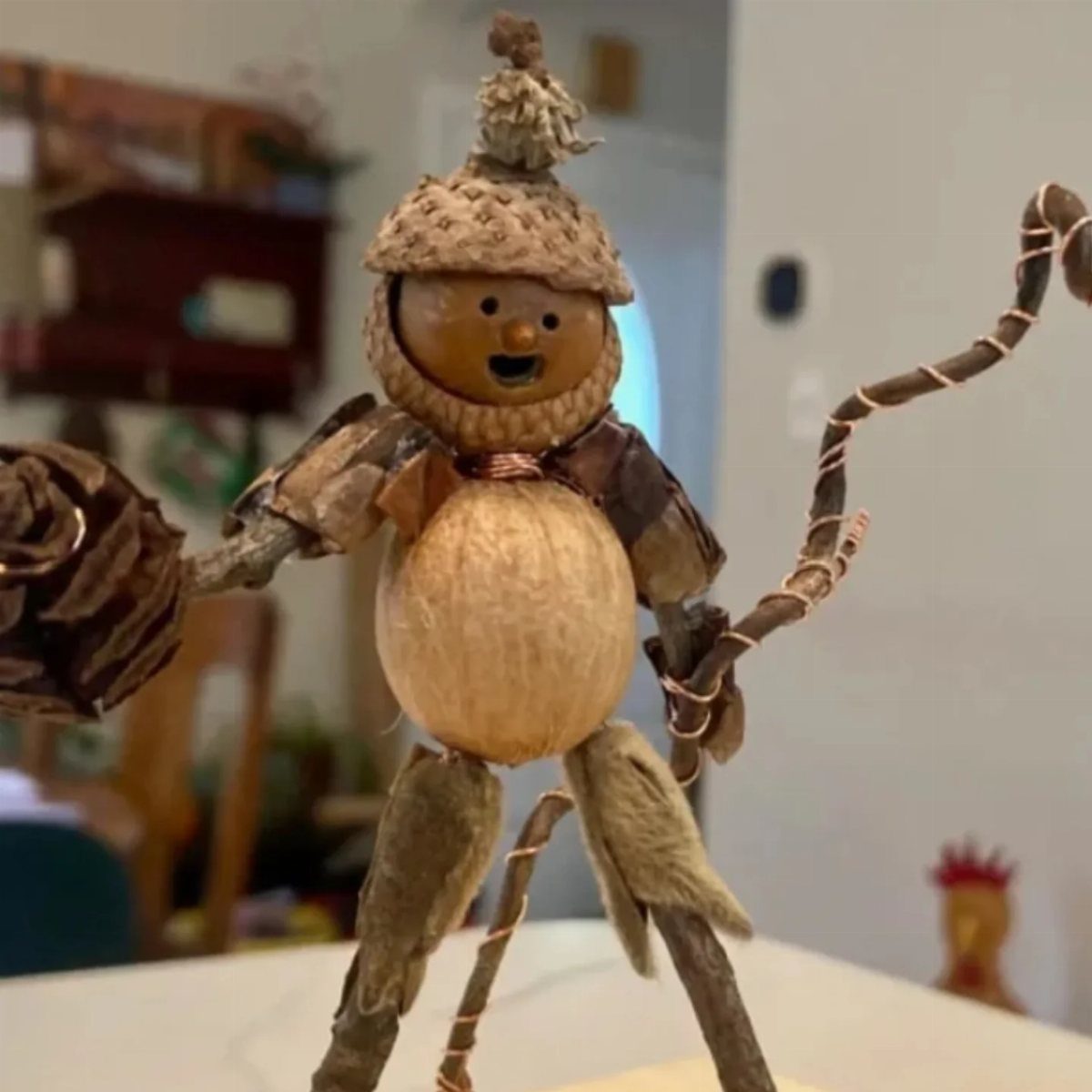 A handmade character crafted from an acorn, coconut shell, and twigs.