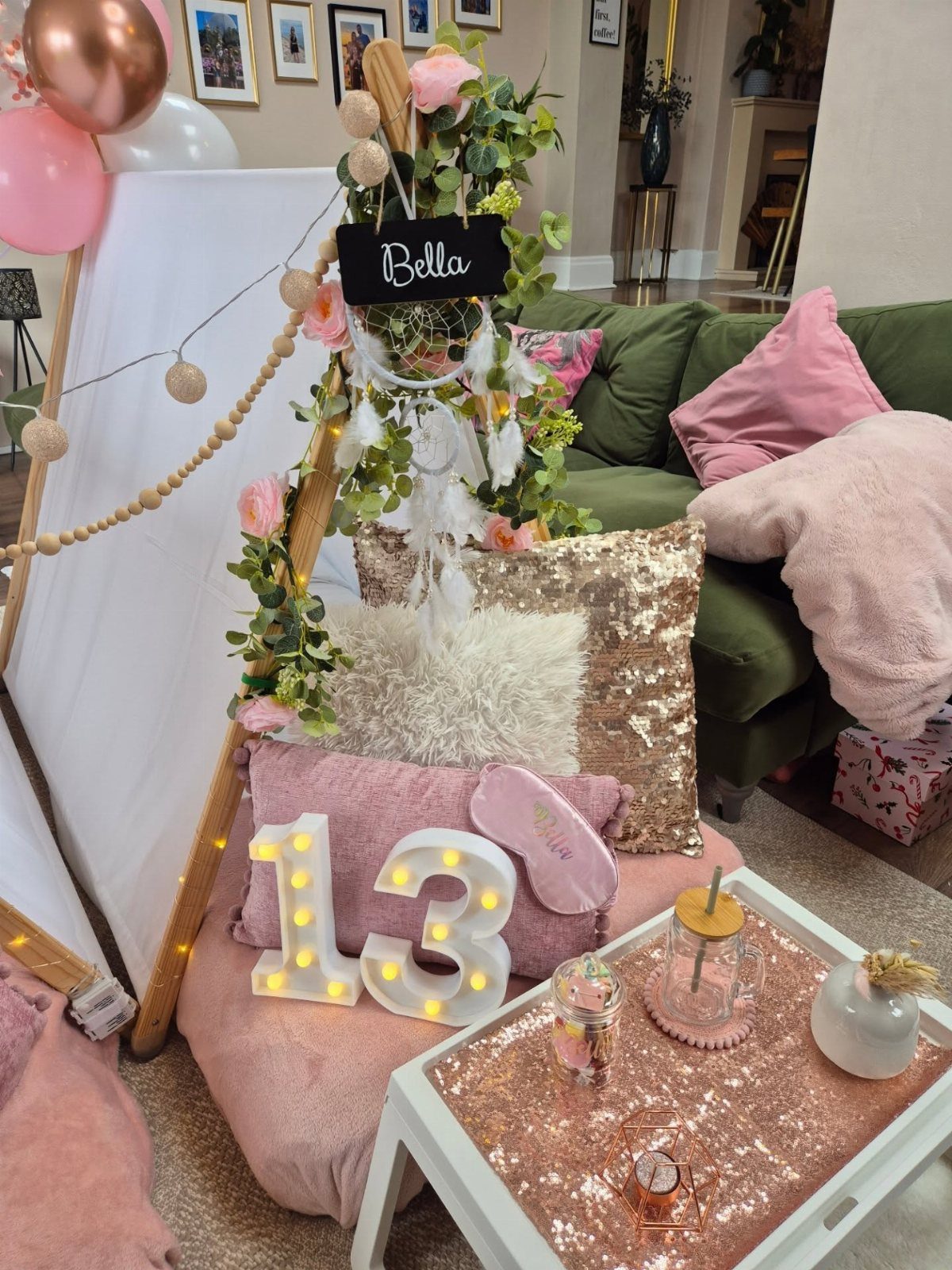 Birthday party decorations with pink balloons, a number 13 light, and a decorated tray on a cushion.