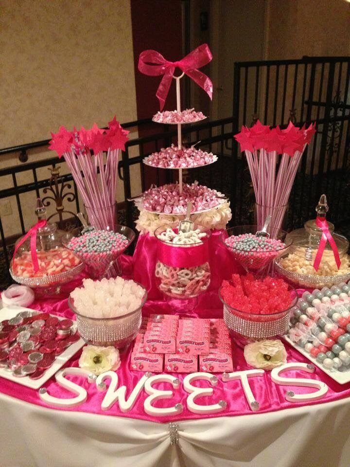 A pink candy buffet table with various sweets in glass bowls and white letters spelling SWEETS.