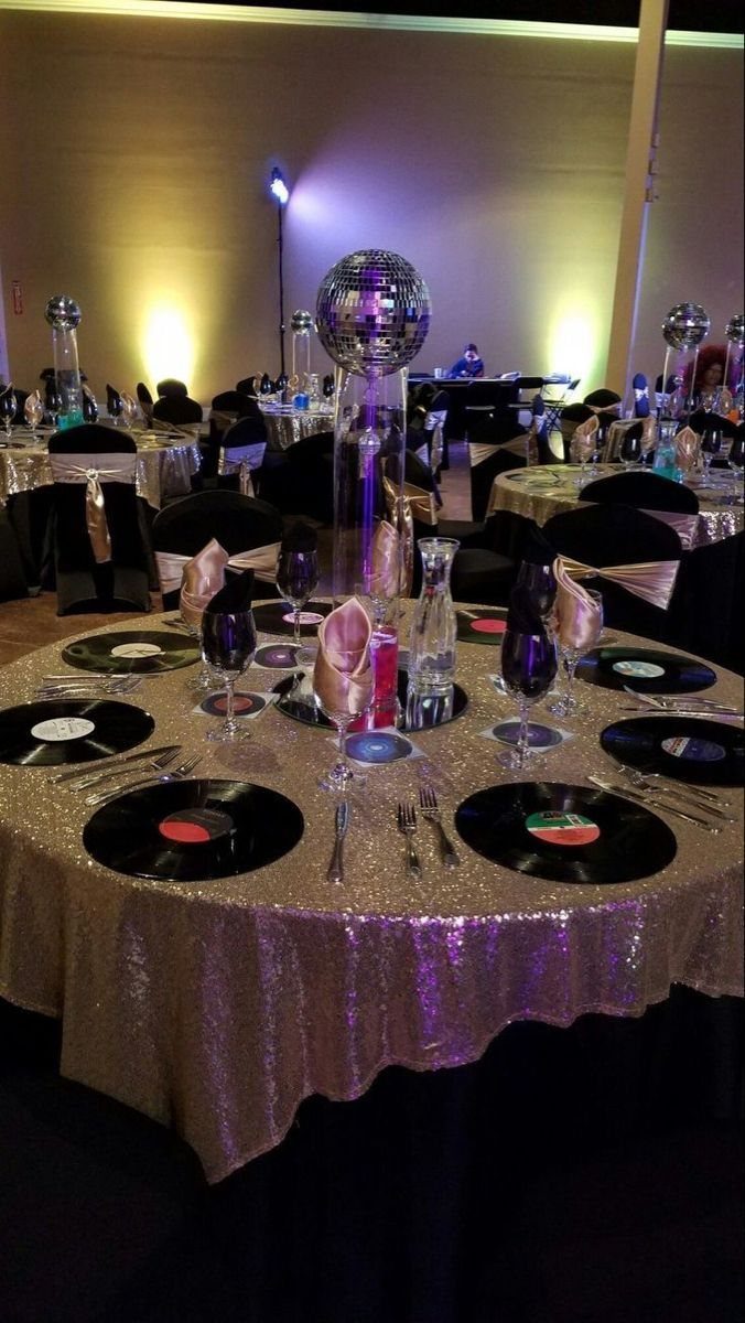 A banquet table with gold sequins, vinyl record plates, and a disco ball centerpiece.