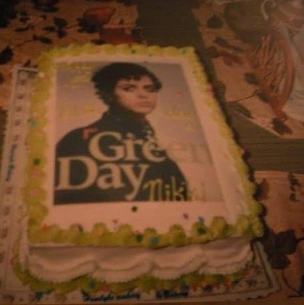 A rectangular sheet cake decorated with an edible Green Day band image and the name Nikki.