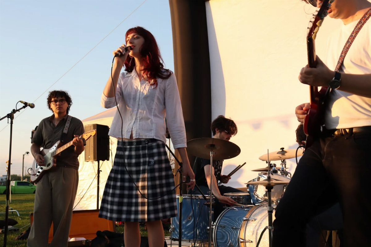 A live band performing on an outdoor stage during a golden sunset.