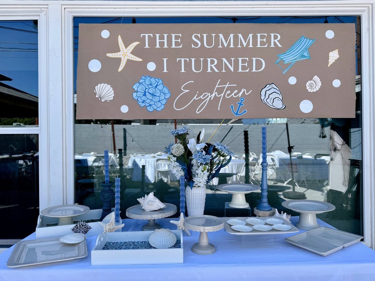 A decorated dessert table featuring a sign celebrating an eighteenth birthday with summer beach themes.