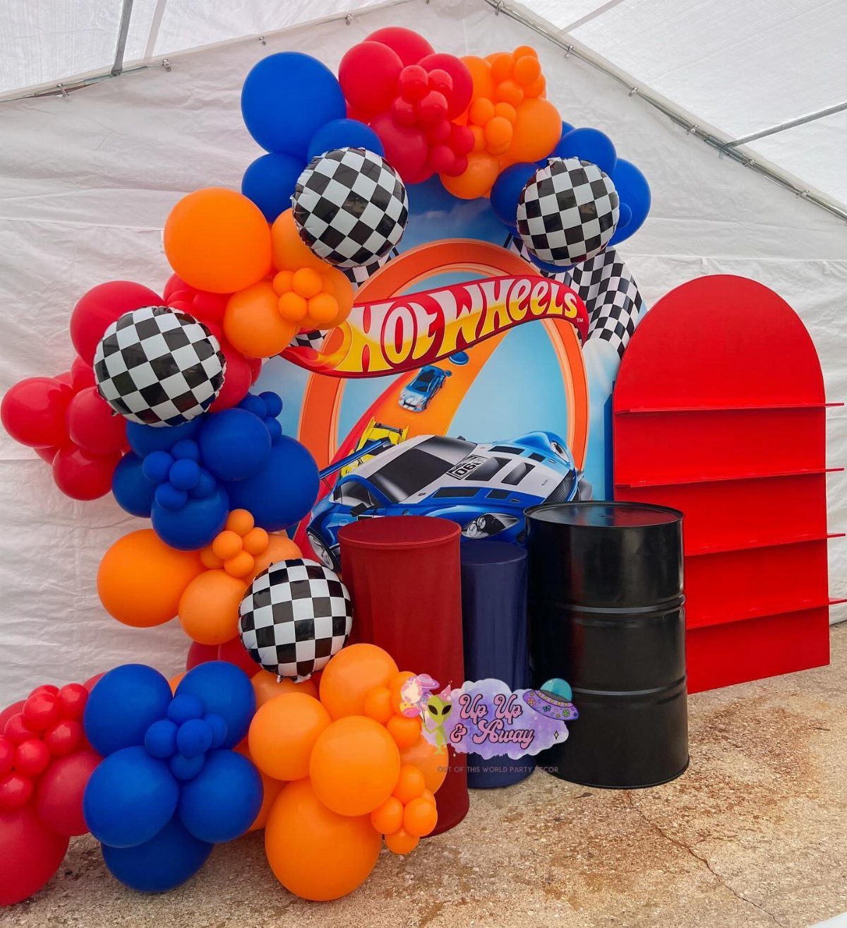 Hot Wheels themed party backdrop with colorful balloon arches and racing car decorations.