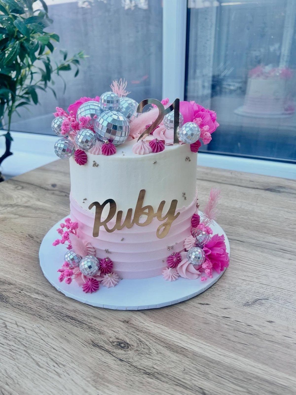 Disco ball cake decorated with pink flowers and a gold '21' topper.