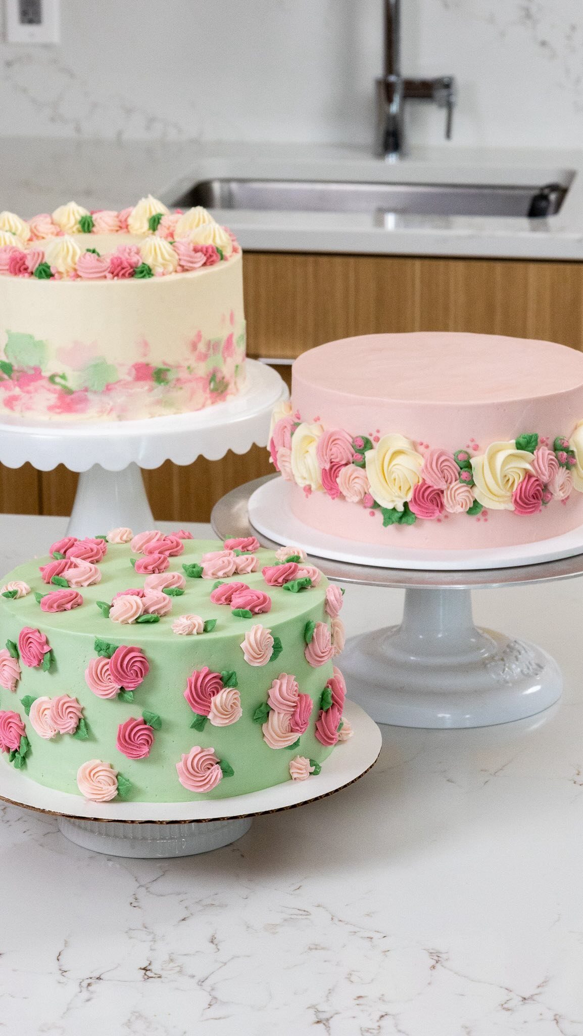 Three elegant floral buttercream cakes in pastel colors.