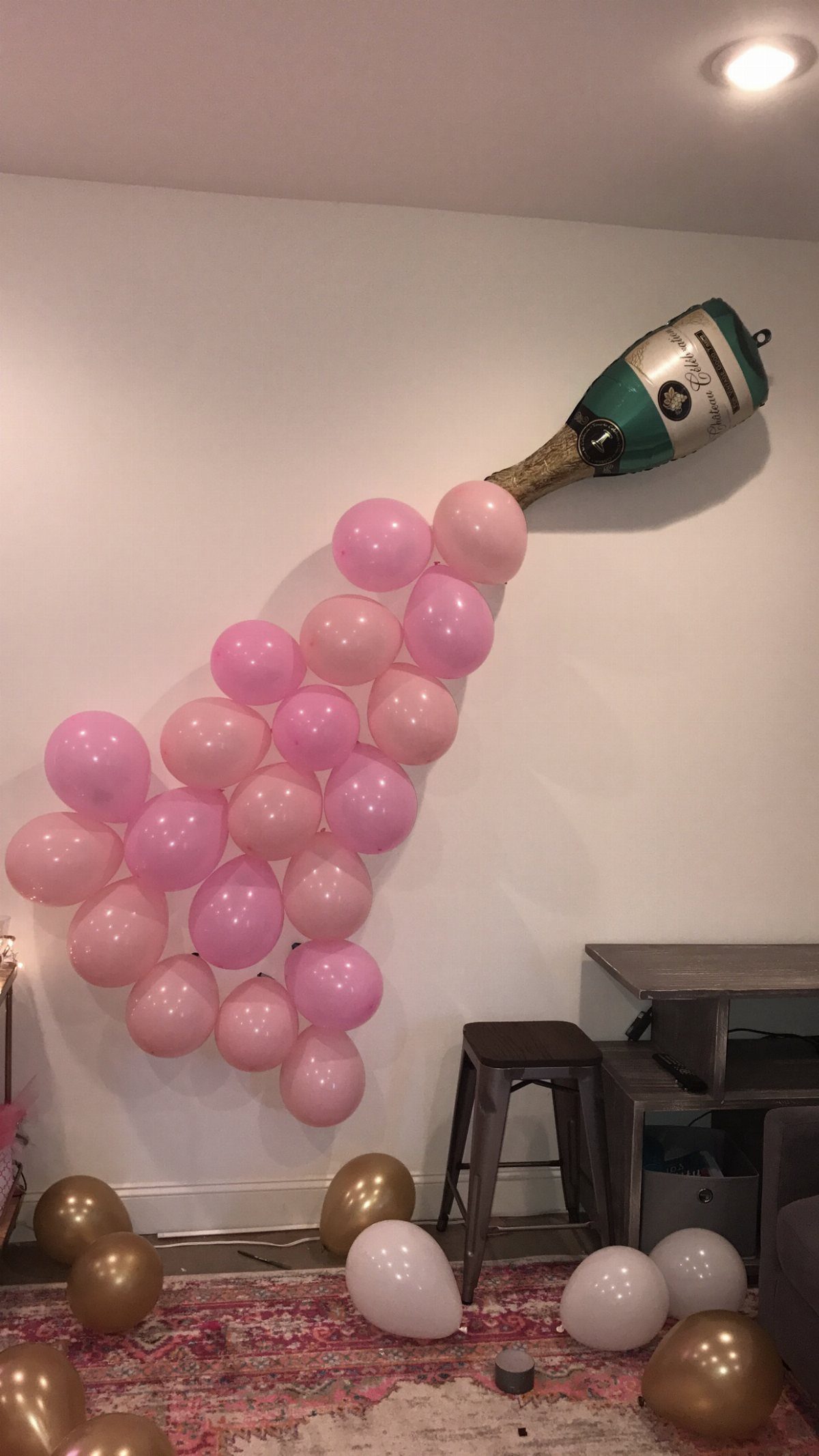Pink balloons shaped like a champagne bottle with scattered balloons on the floor.