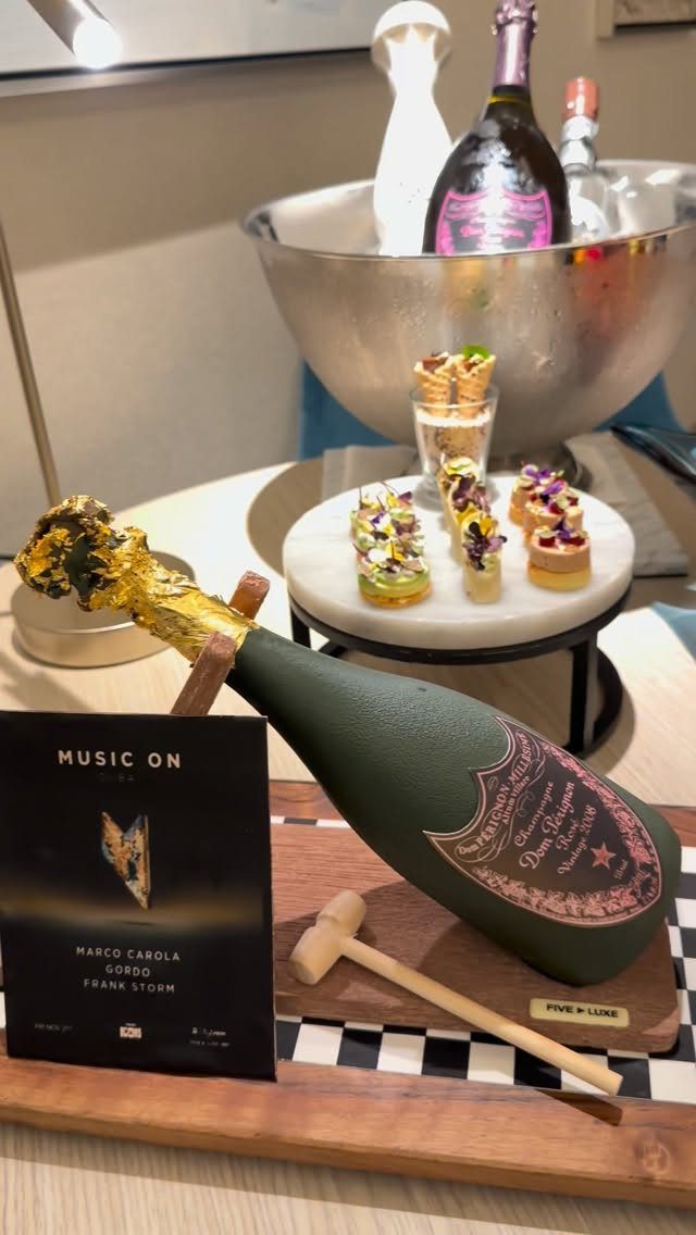 A green champagne bottle with a gold foil top and a small wooden mallet on a tray.