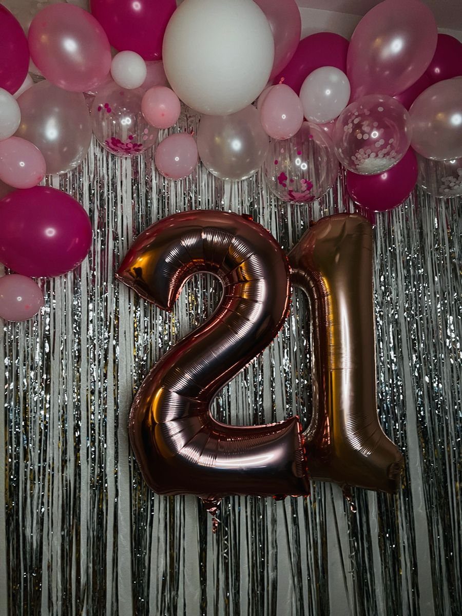Sequin backdrop with pink and white balloons and large '21' balloons.