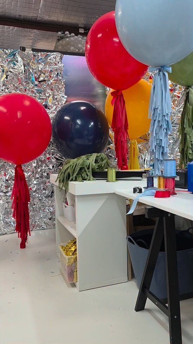 Decorative balloons with tassel tails in vibrant colors against a shiny backdrop.