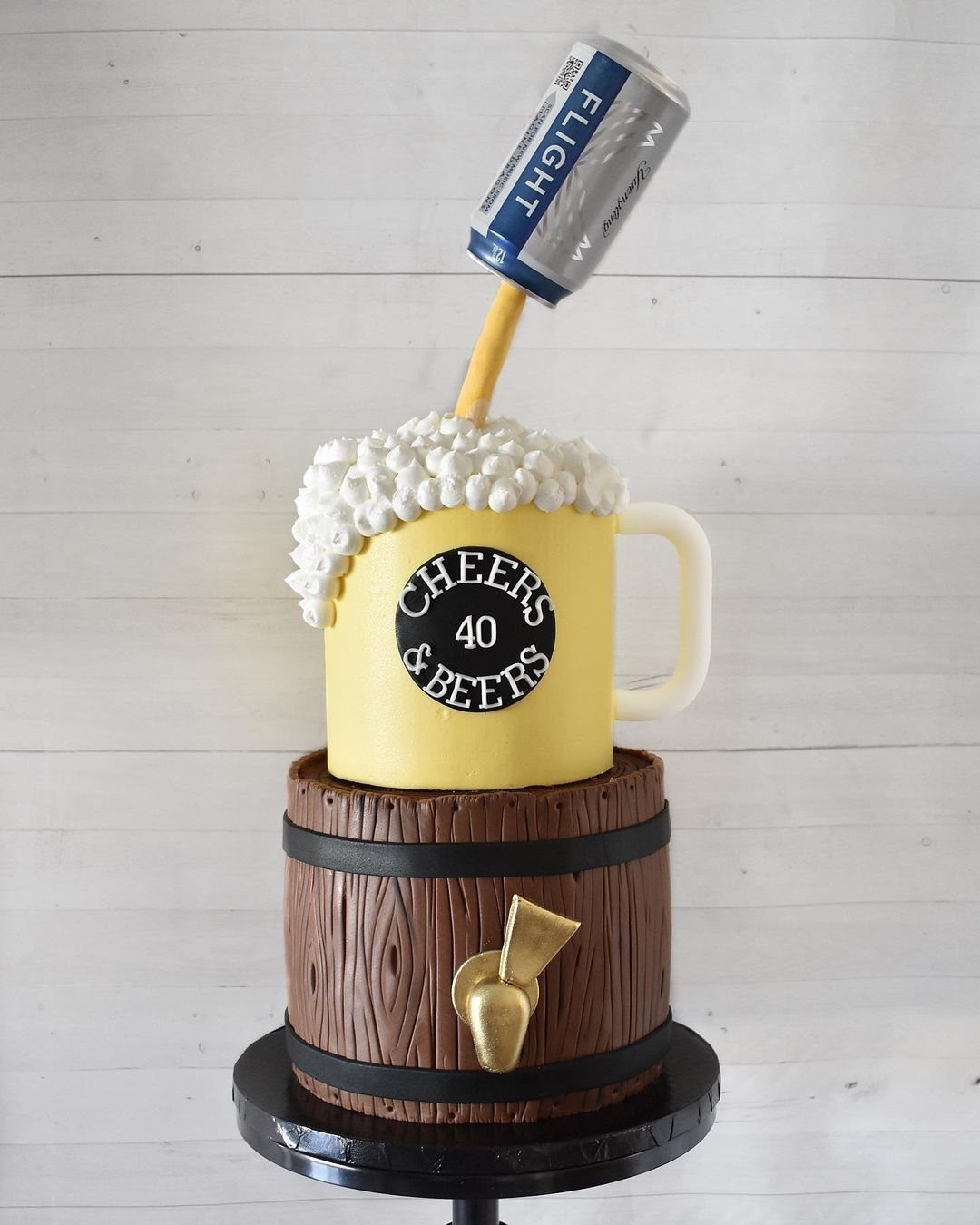 Beer barrel cake with a yellow mug and foam, set against a wooden background.