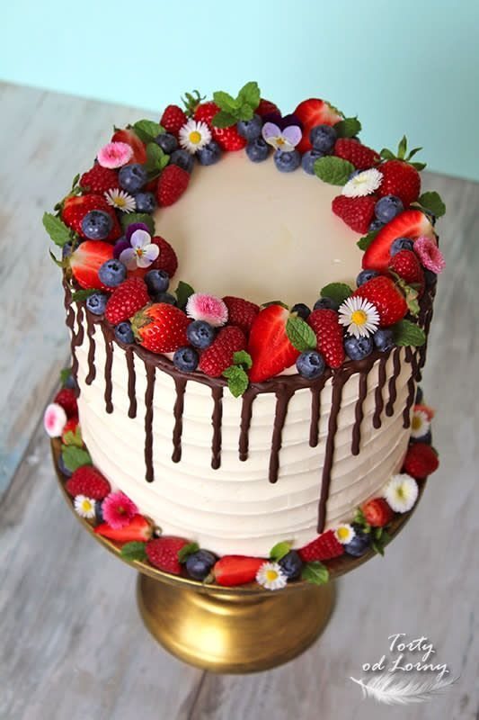 Multi-layered cake decorated with fresh berries and flowers.
