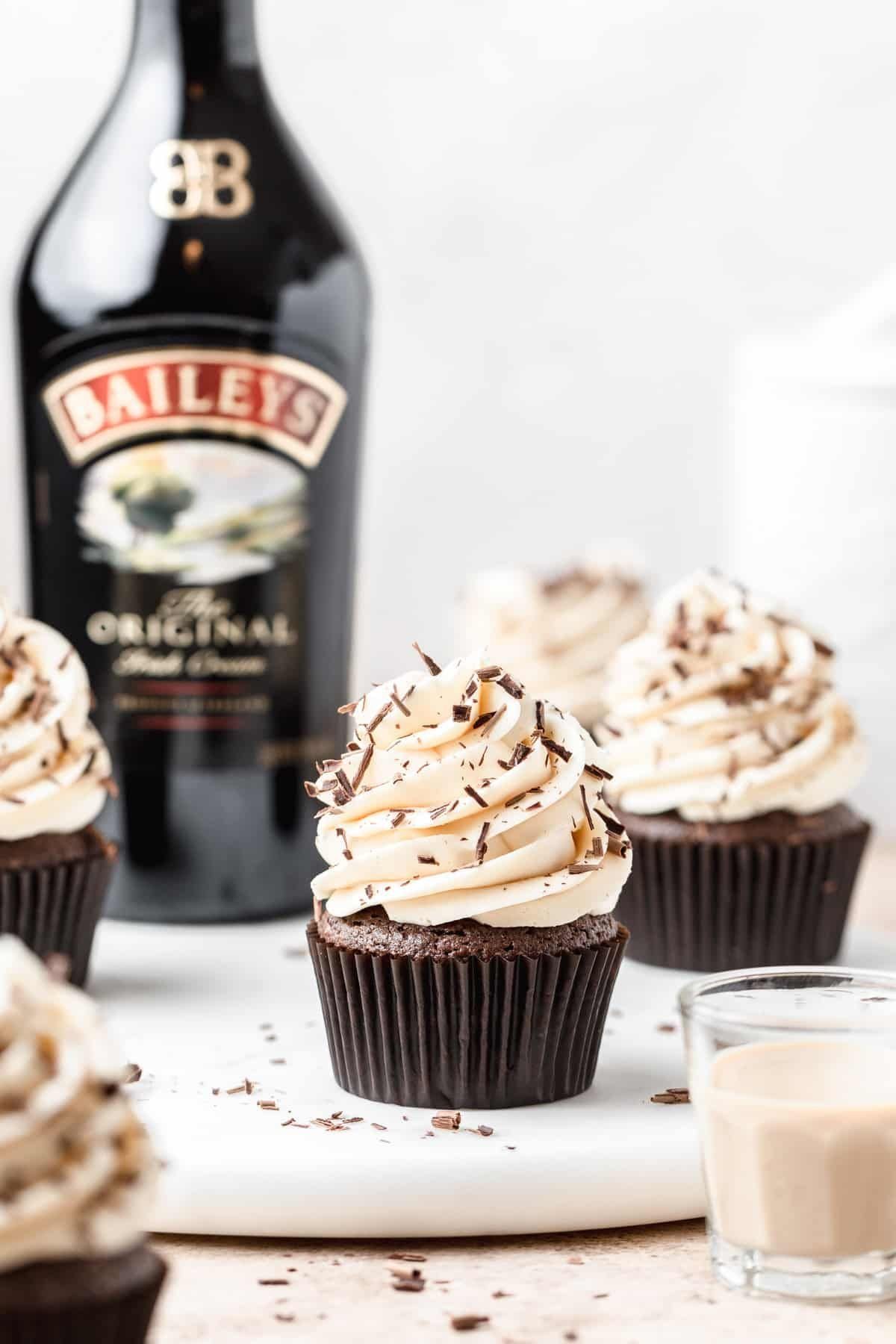 Chocolate cupcakes with cream frosting and Baileys Irish Cream bottle.