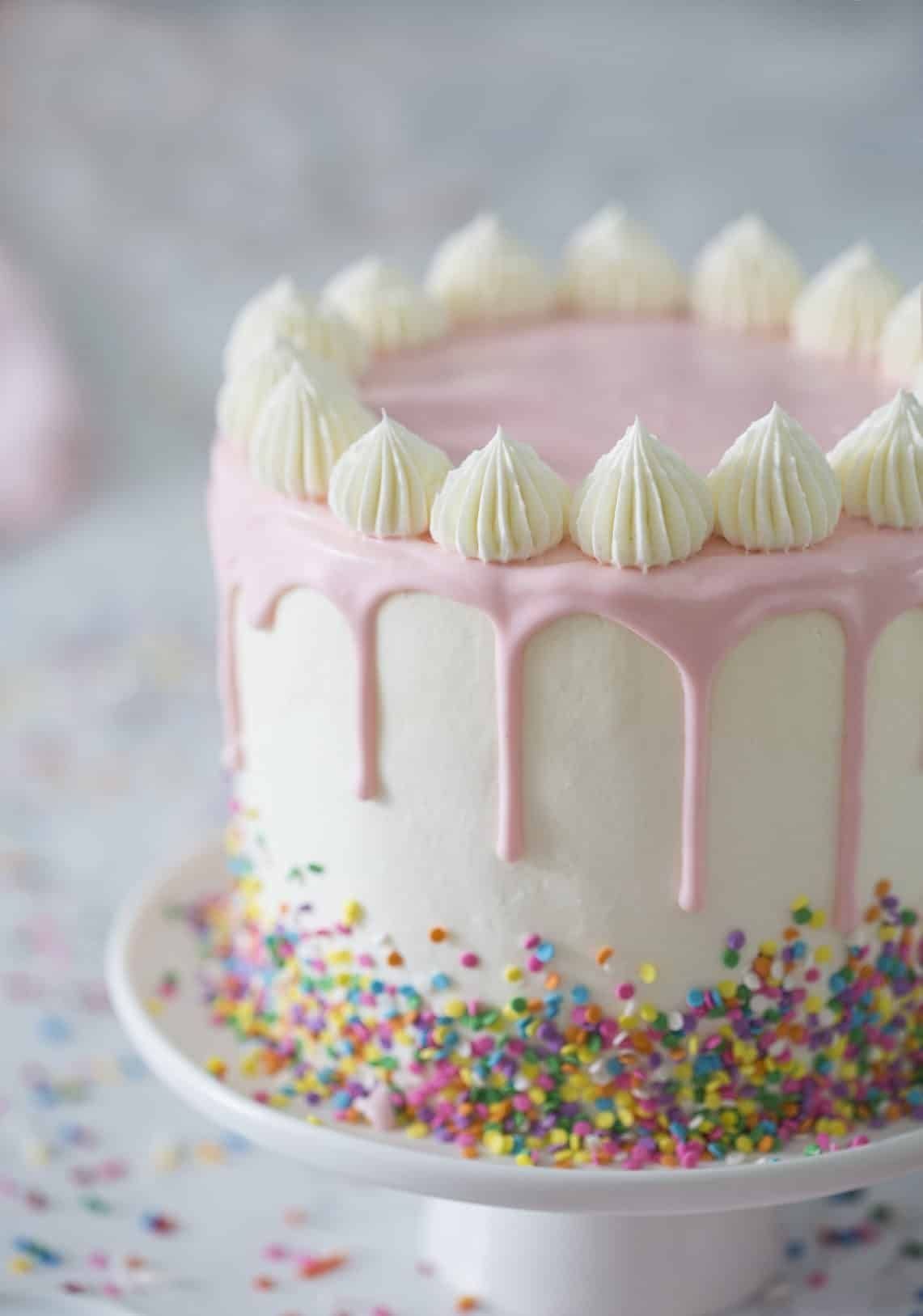 Funfetti cake with pink drip icing and colorful sprinkles.
