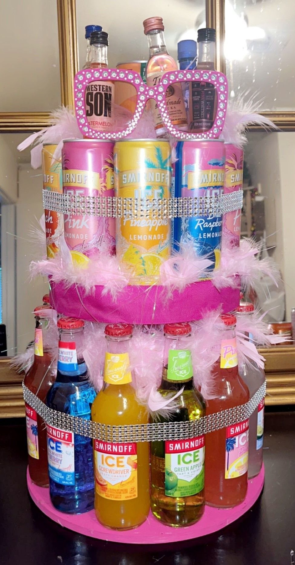 Tiered cake display with colorful Smirnoff bottles and pink decorations.