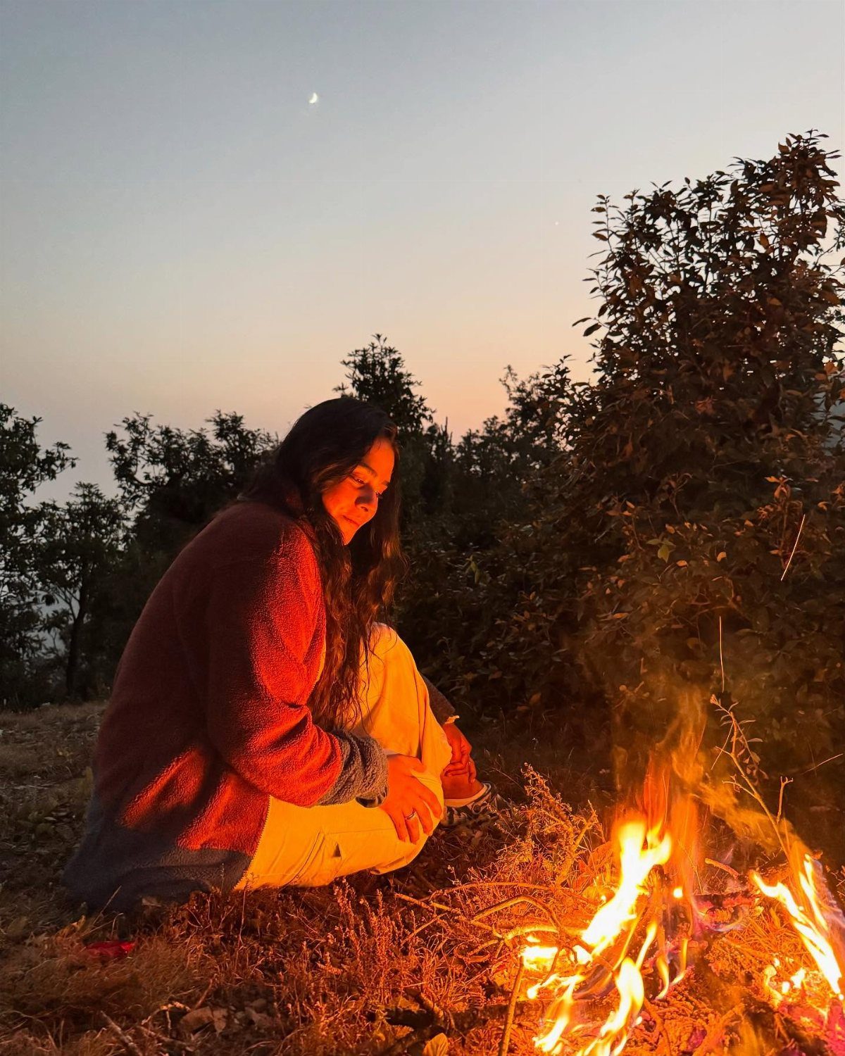 Person enjoying a campfire in a serene outdoor setting.