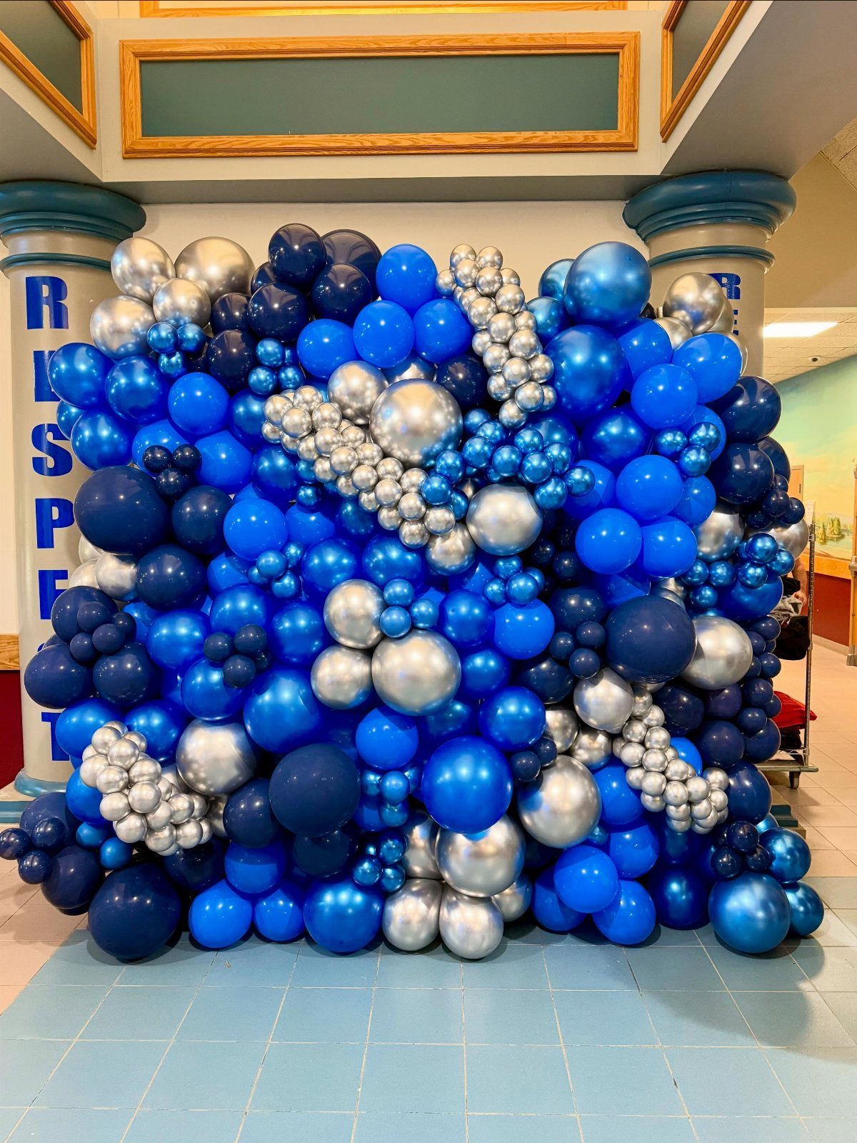 A large decorative wall made of blue and silver balloons of various sizes.