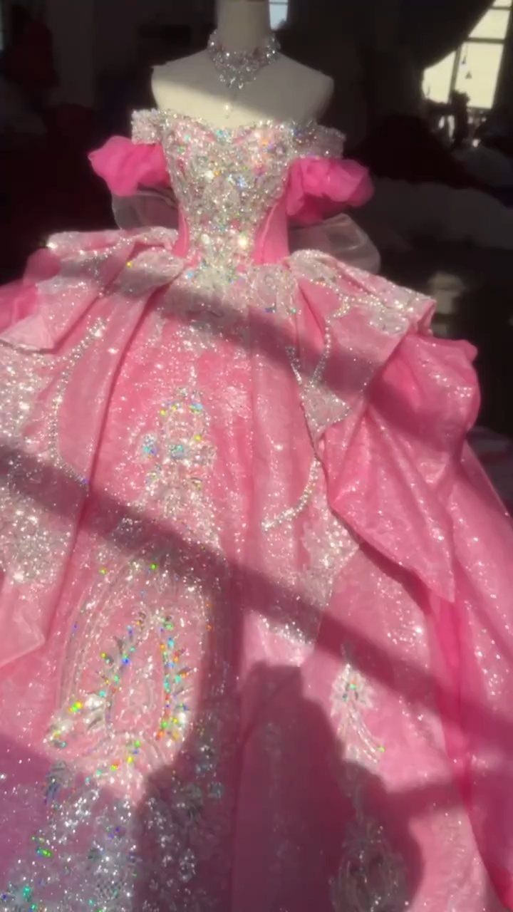 A sparkling pink princess ball gown with silver embellishments on a mannequin.