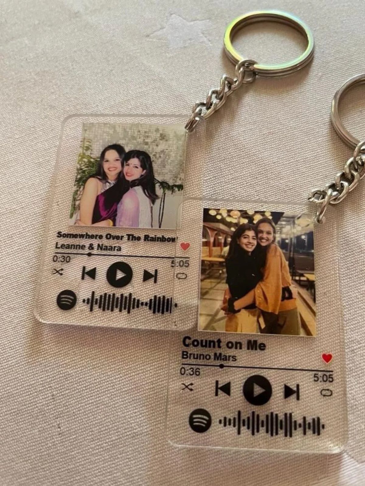 Two custom acrylic keychains featuring printed photos of women and music player graphics.