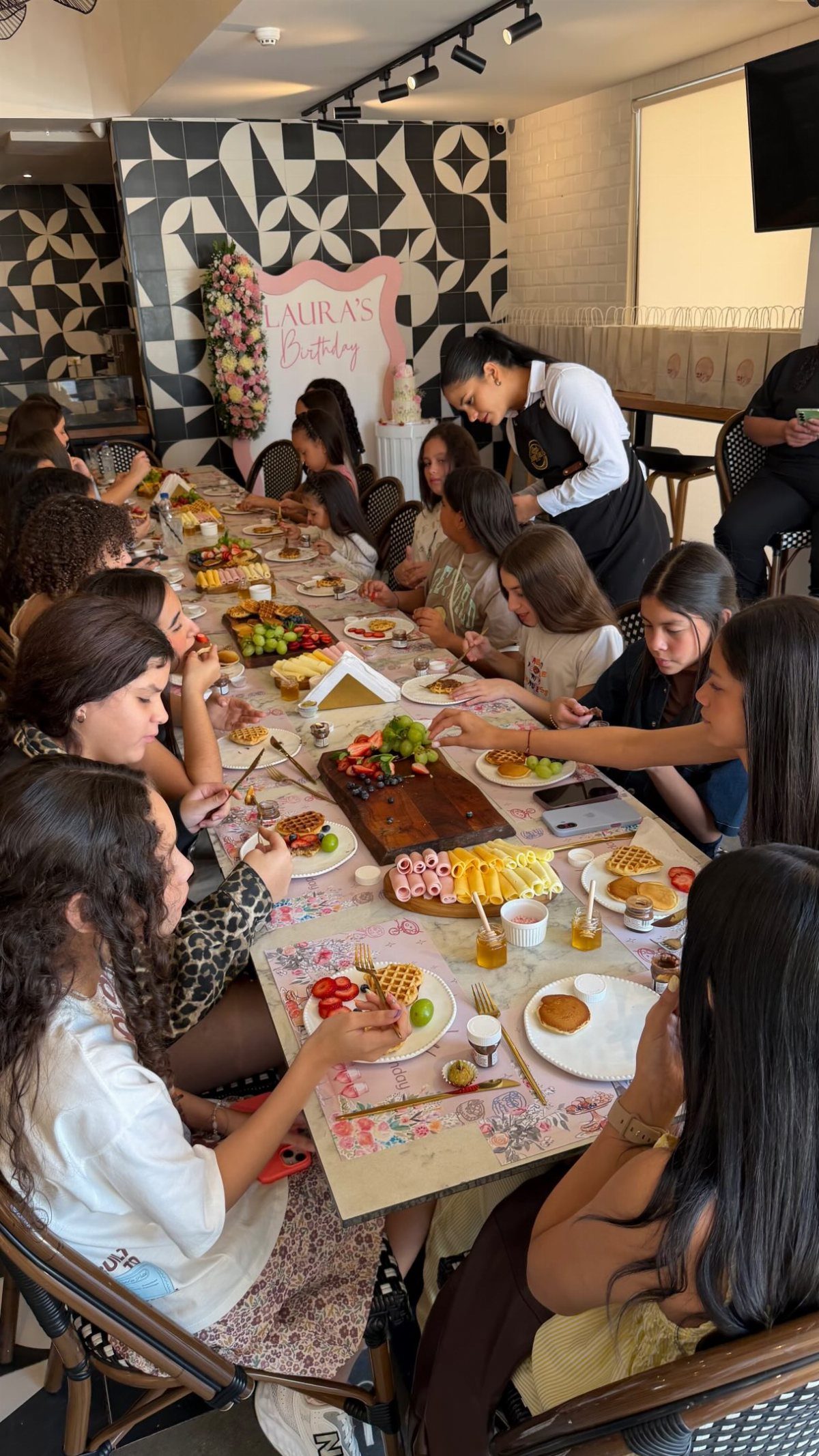 A group of women enjoying a large brunch spread at a long table indoors.