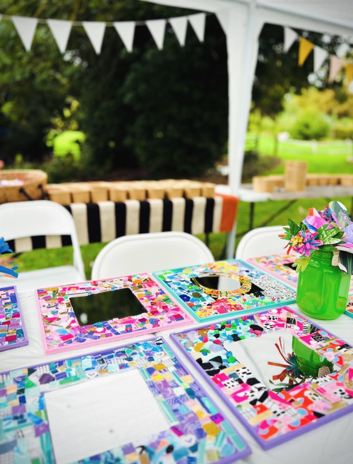 Colorful mosaic picture frames arranged on a white table under a party tent.