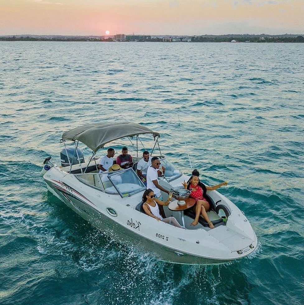A group of friends enjoying a motorboat ride on the ocean during a scenic sunset.