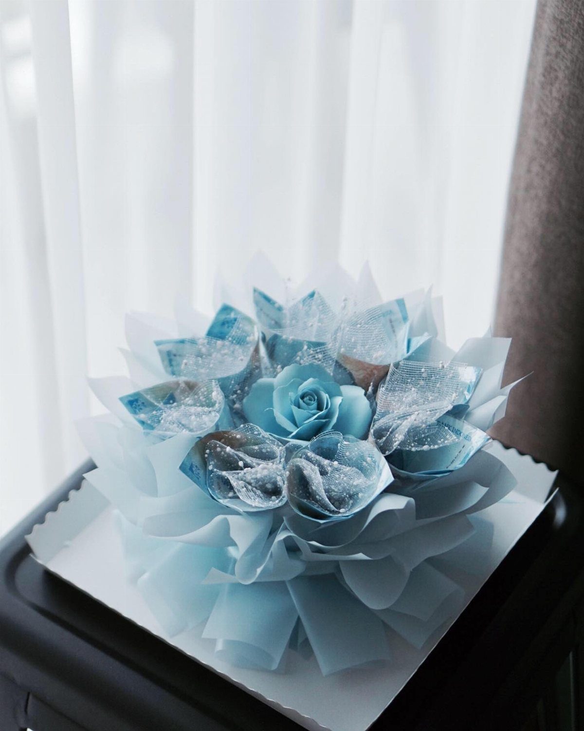 A decorative bouquet crafted from folded blue banknotes arranged in a floral shape.