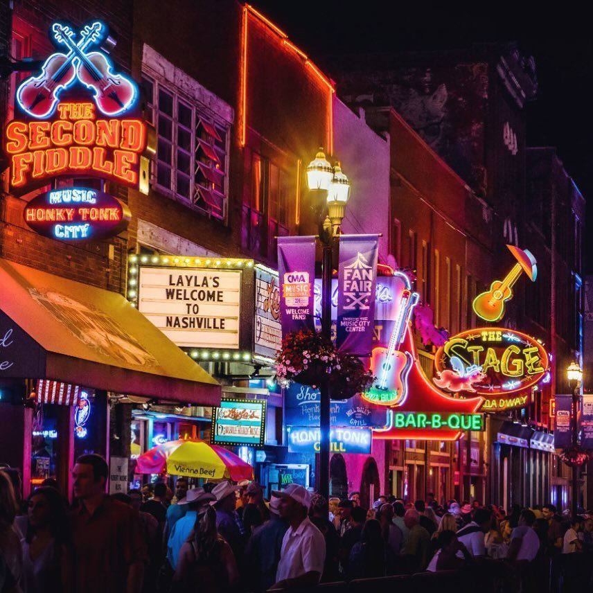 Bright neon signs and crowds of people on a busy Nashville street at night.