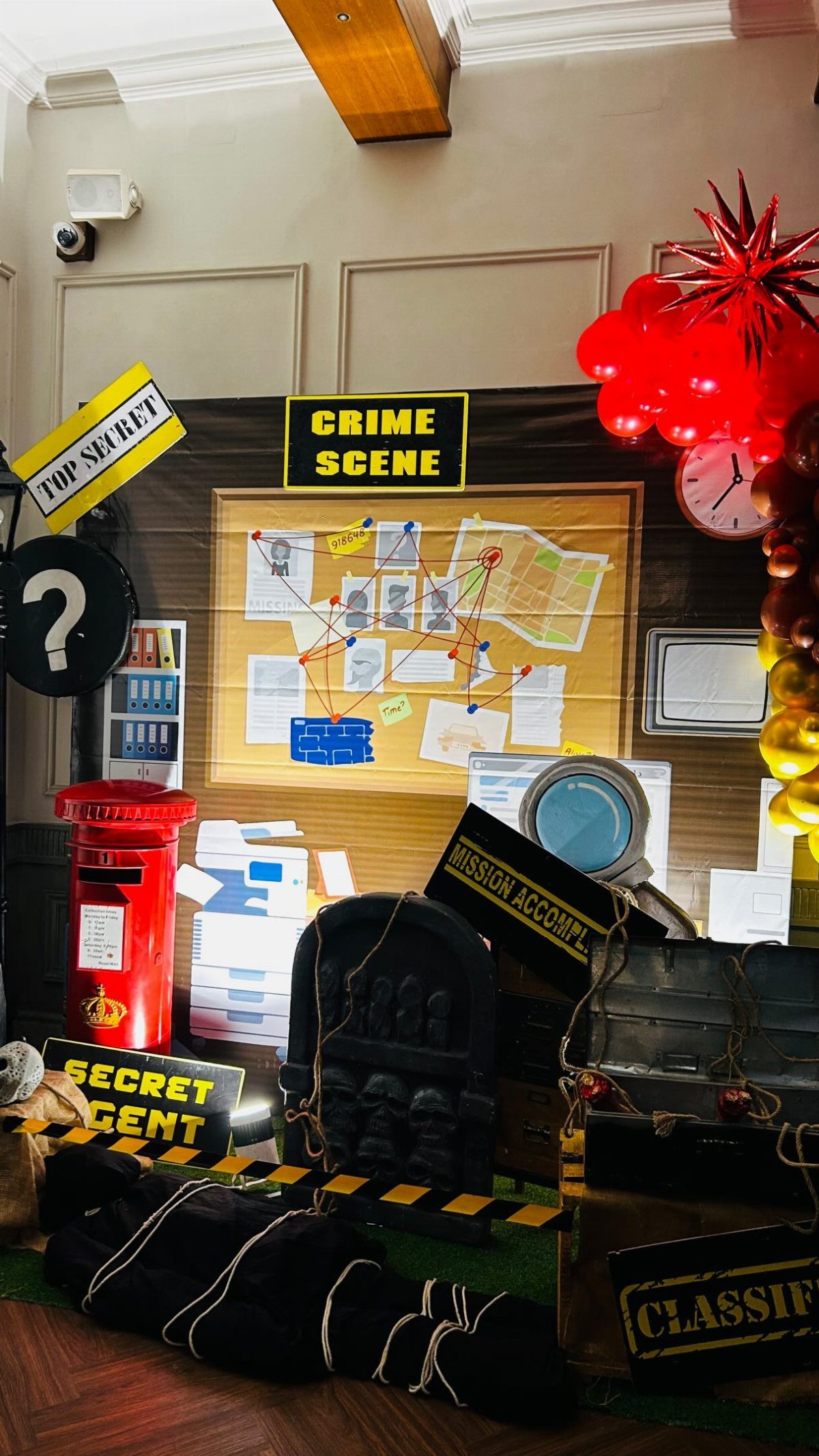 Crime scene themed party decorations including an investigation board, magnifying glass, and caution tape.