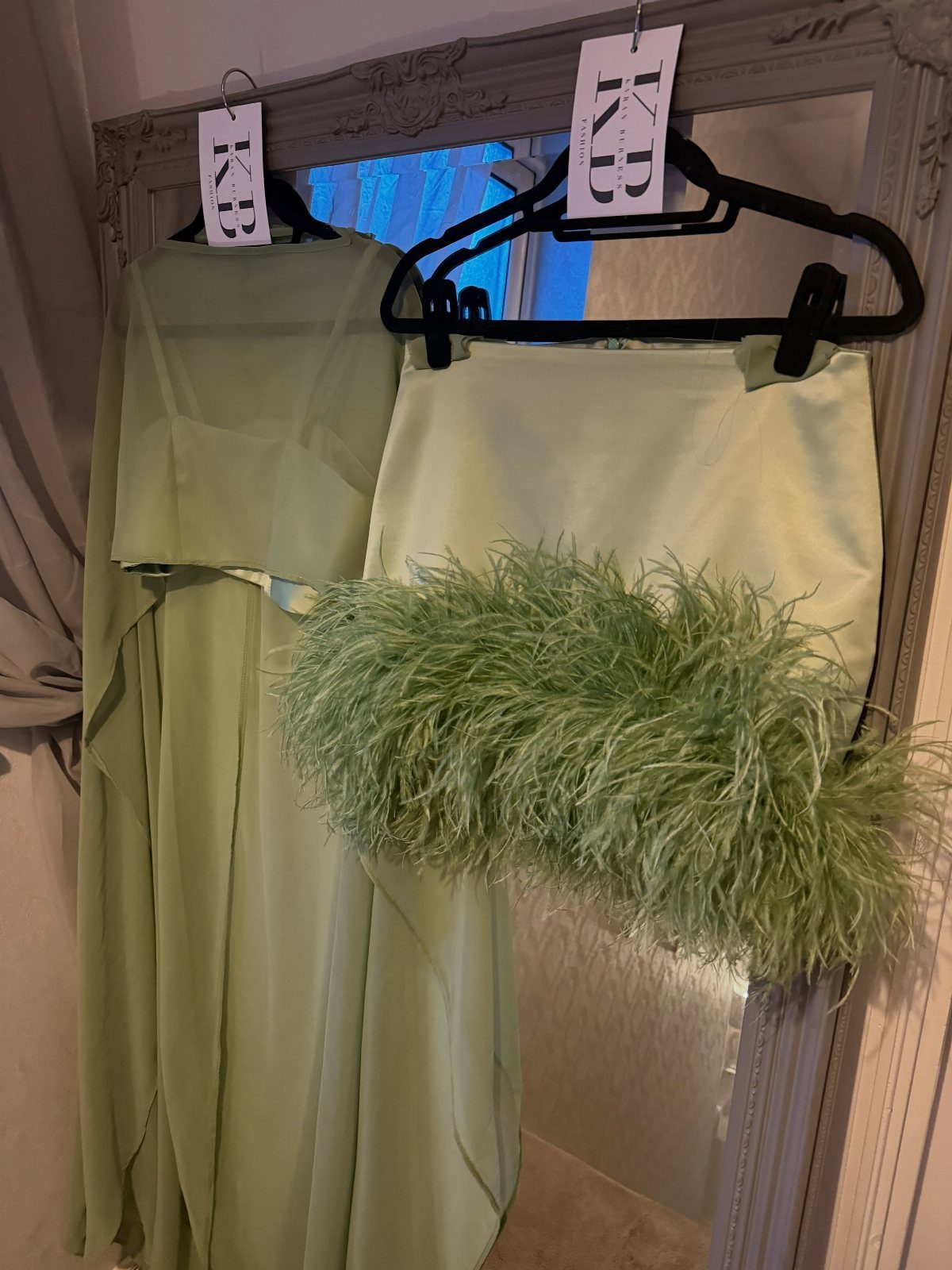 Light green two-piece outfit featuring a top with thick feather trim hanging on a mirror.