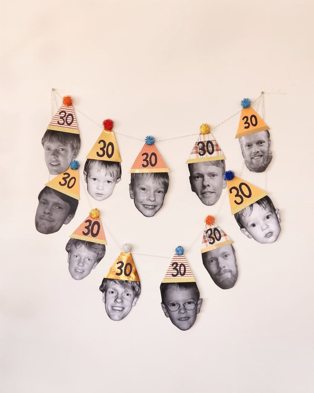 A garland of party hats featuring children's faces and the number 30 hanging on a wall.