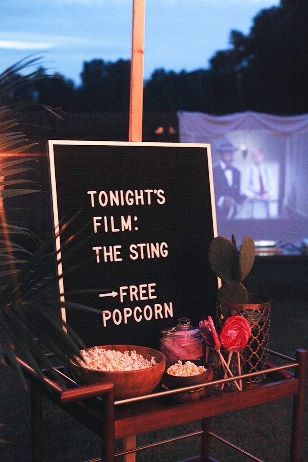 A chalkboard sign announcing a film screening with bowls of popcorn on a tray.