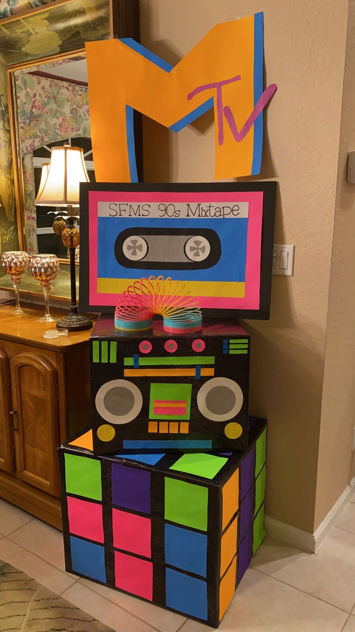 Colorful 90s themed decorations featuring an MTV logo, cassette tape, boombox, and Rubik's cube.