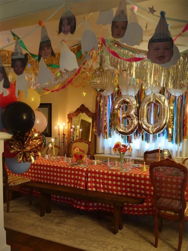 A decorated dining table with red checkered cloth and large gold number thirty balloons.