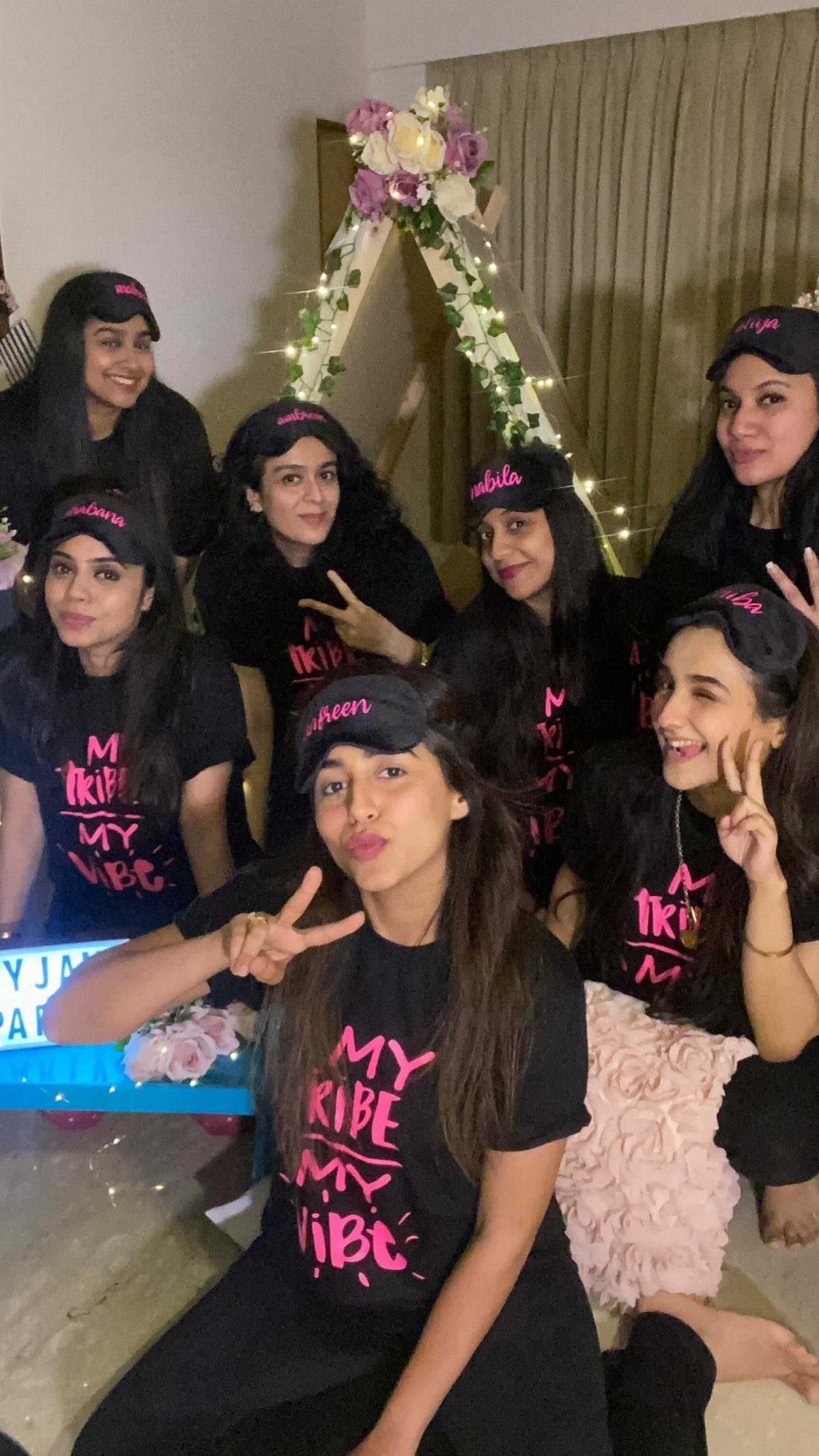 Seven women in matching black t-shirts and sleep masks posing together for a group photo.