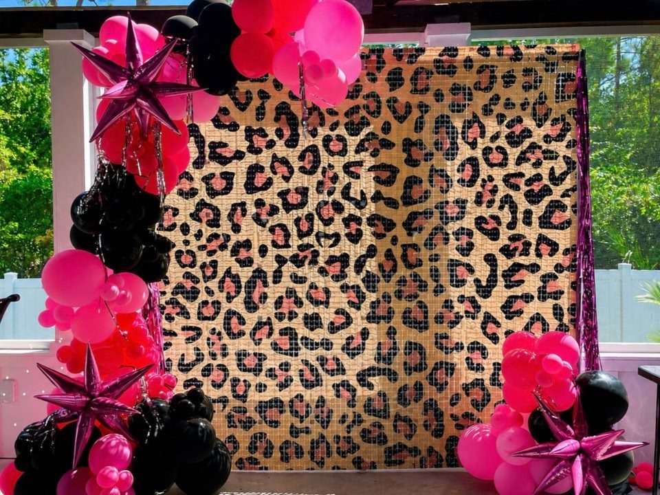 Leopard print backdrop decorated with pink and black balloons and metallic pink stars.