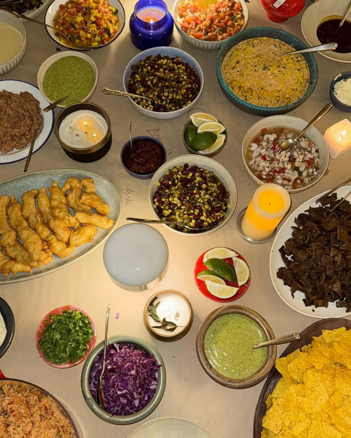 A variety of Mexican dishes including salsa, guacamole, beans, and corn salad arranged on a table.