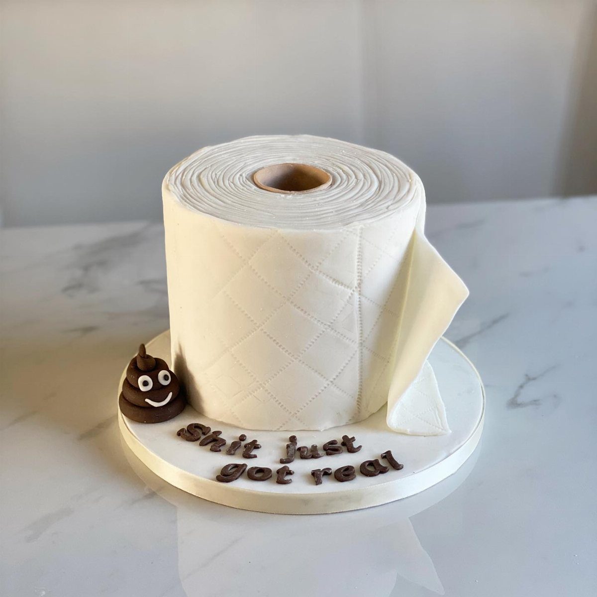A cake designed to look like a roll of white toilet paper with chocolate decorations.