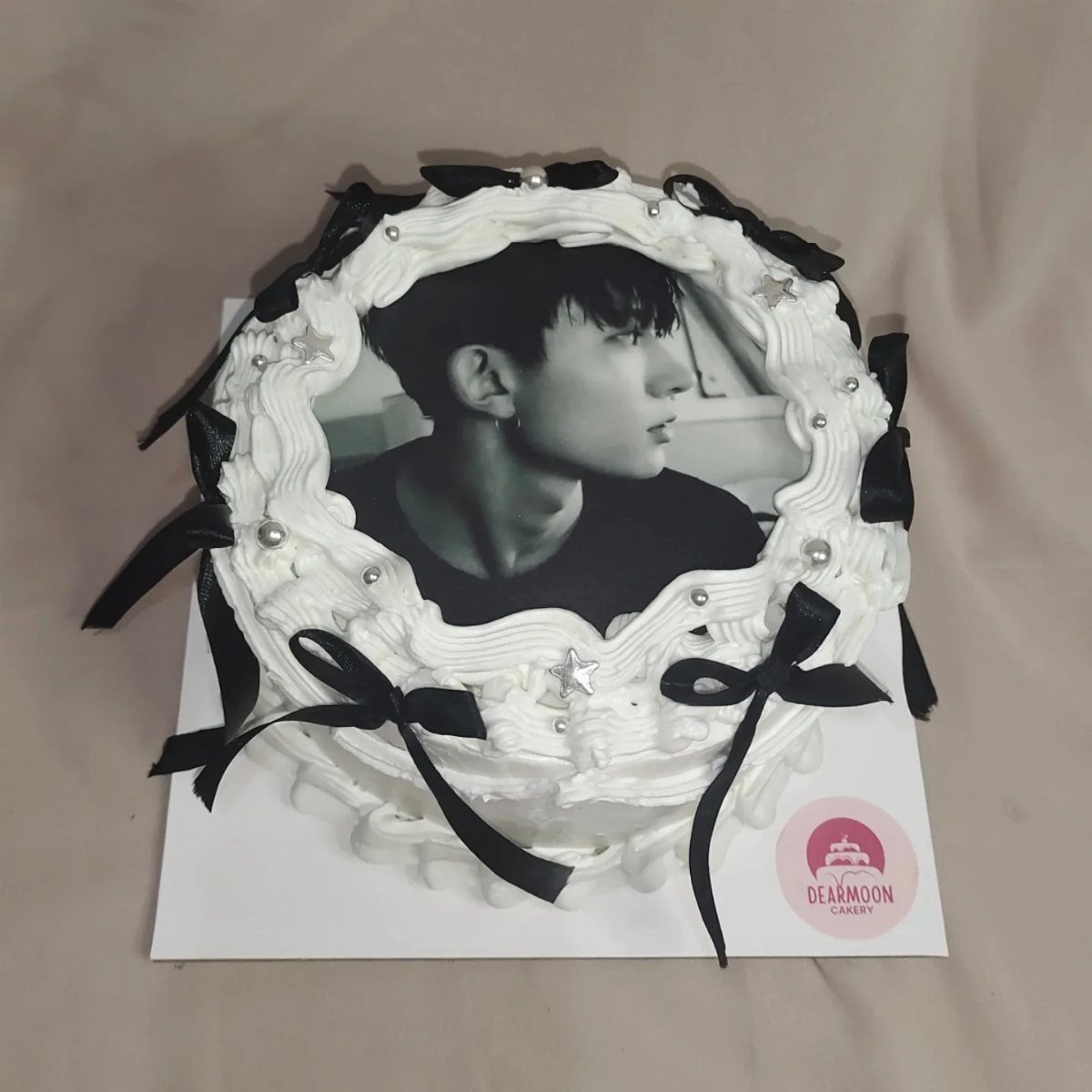 A white frosted cake featuring a large black and white edible photo of a man.