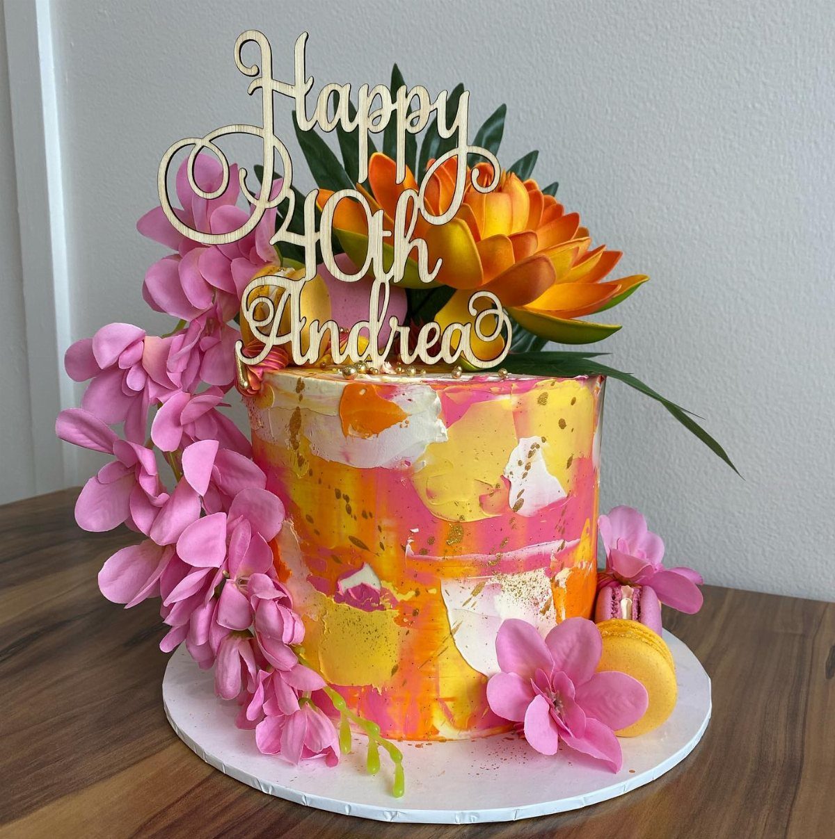 A colorful tropical themed 40th birthday cake with orange flowers and pink accents.