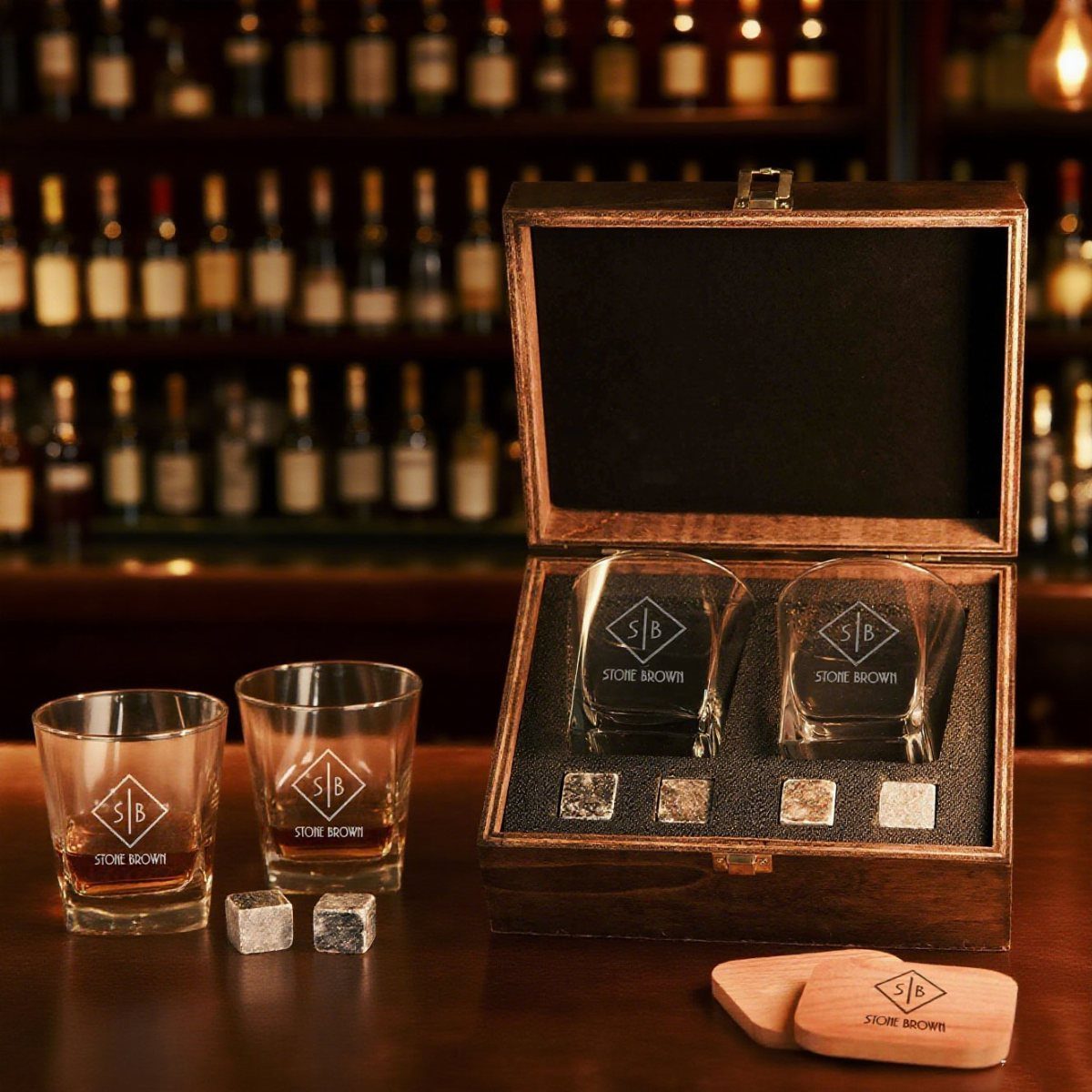 Engraved whiskey glasses and stones in a wooden gift box on a bar counter.