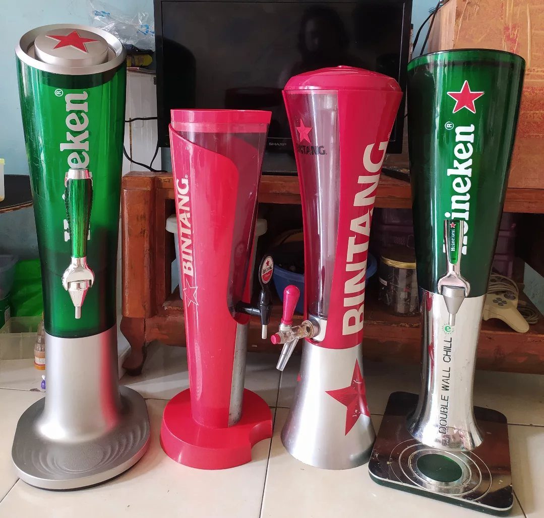 Four branded beer dispensers in green and red standing on a tiled floor.