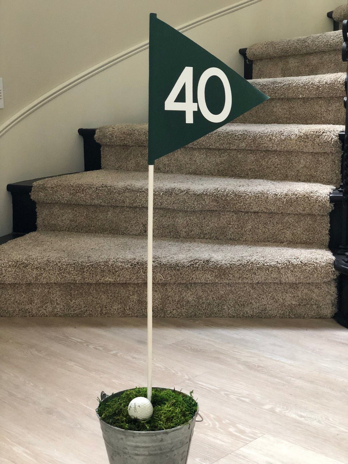 A green golf flag with the number 40 in a small metal bucket with moss.