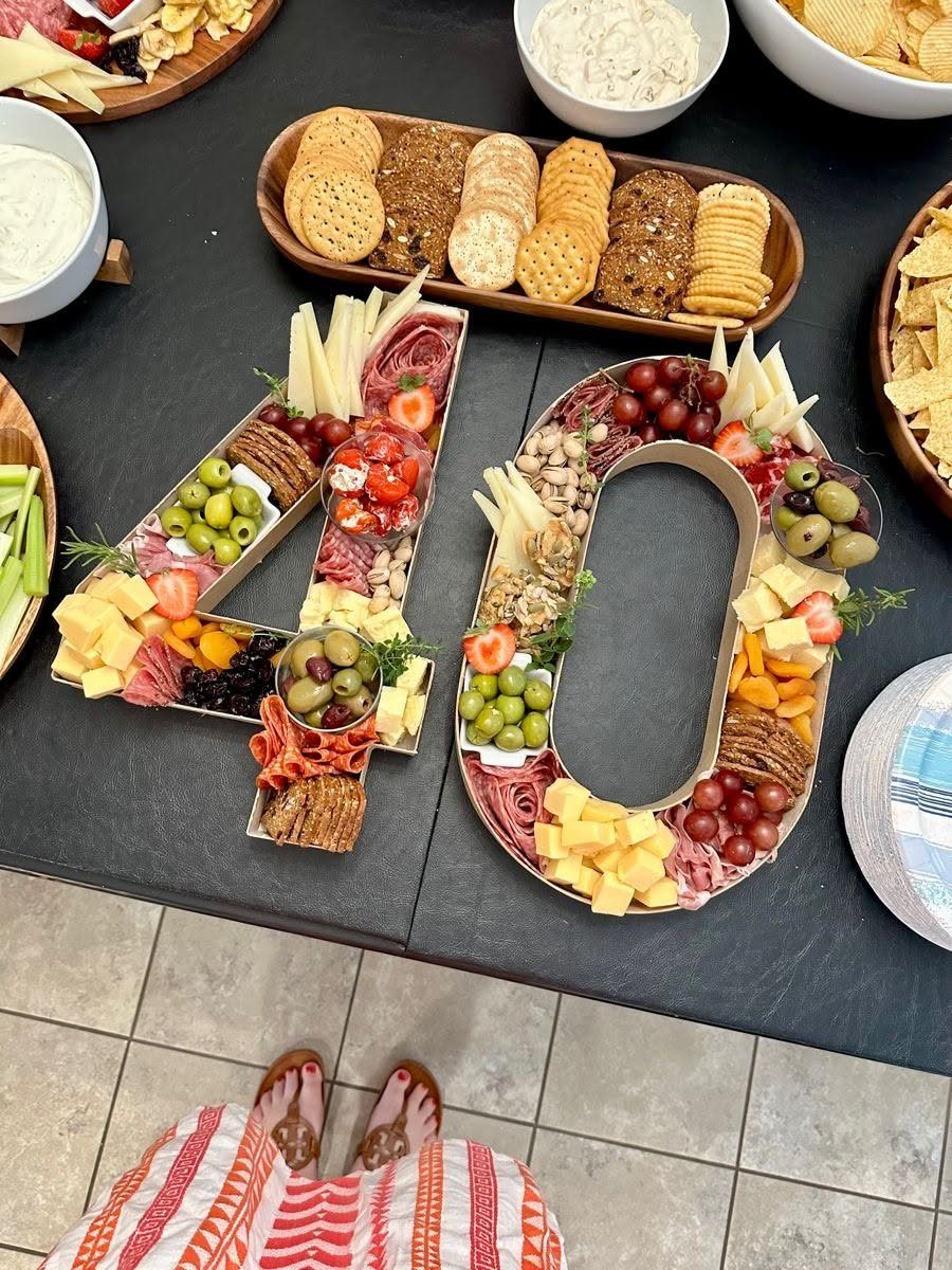 Charcuterie board shaped like the number 40 filled with meats, cheeses, olives, and crackers on a table.