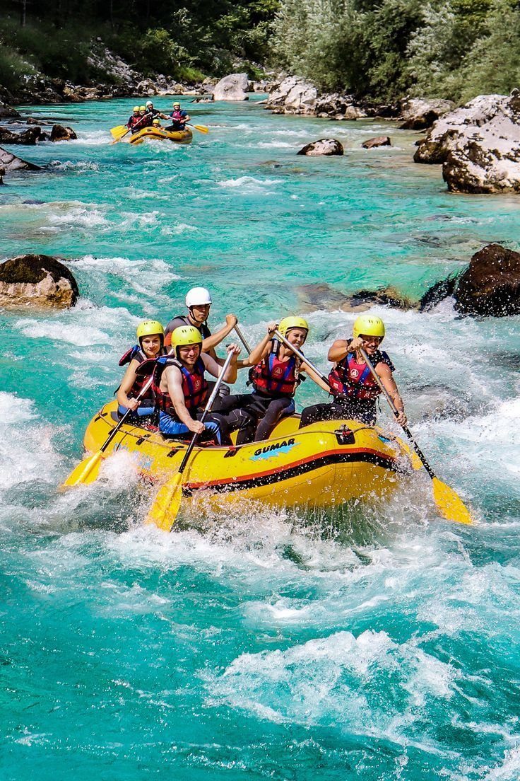 People in a yellow raft paddling through turquoise river rapids with white water splashing.