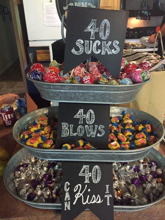 Three metal trays filled with candies, featuring humorous signs for a 40th birthday.