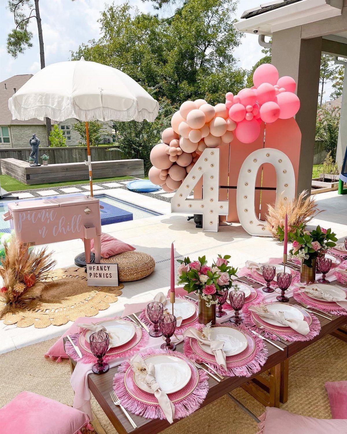 Pink themed outdoor table setting with large light-up number forty and balloon arch.