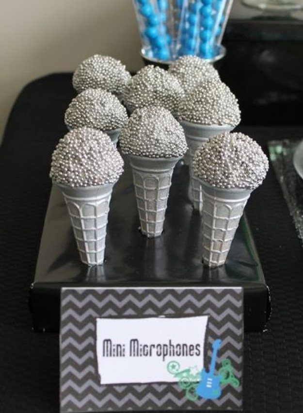 Silver beaded treats shaped like microphones on cones resting on a black display stand.