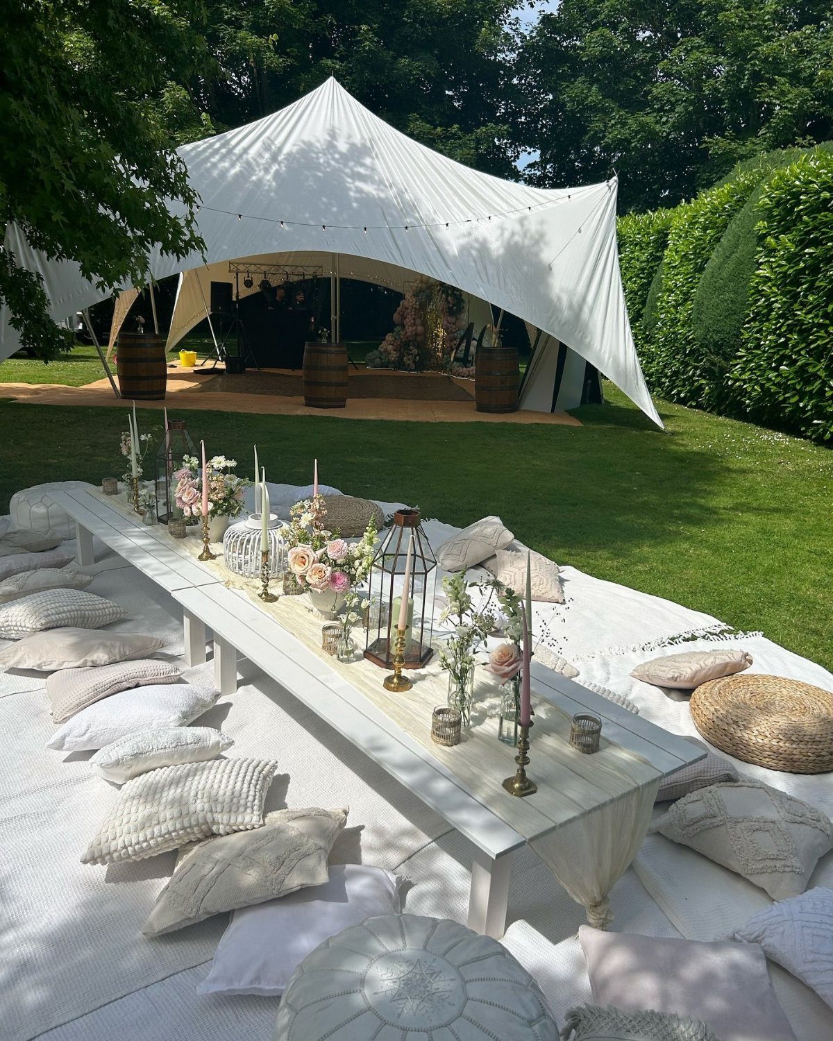 A beautifully arranged outdoor dining setup with a white tent and decorative elements.